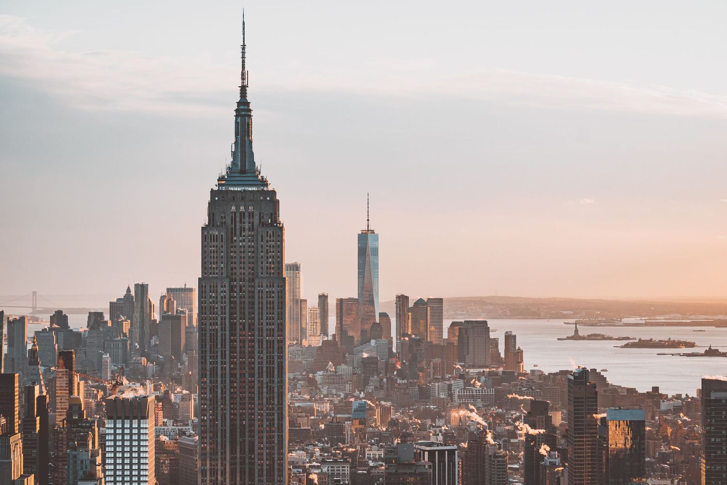 New York City skyline at sunset with iconic Empire State Building and surrounding skyscrapers.