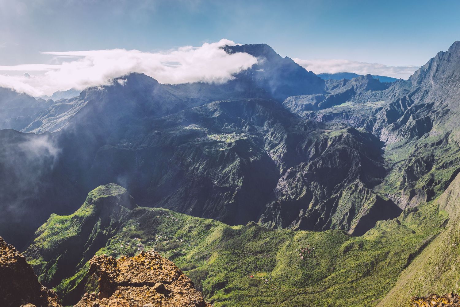 Dramatic mountain landscape with lush green valleys and peaks shrouded in clouds in Reunion island.