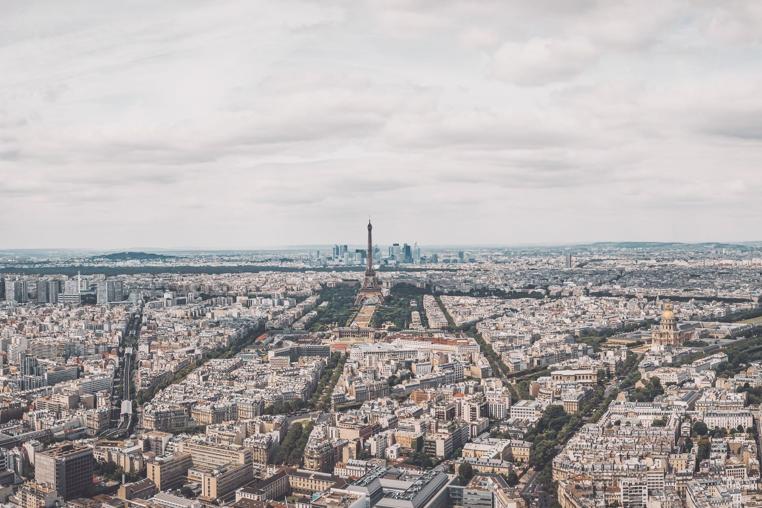 Wide aerial view of Paris cityscape showing urban planning and the Eiffel Tower.