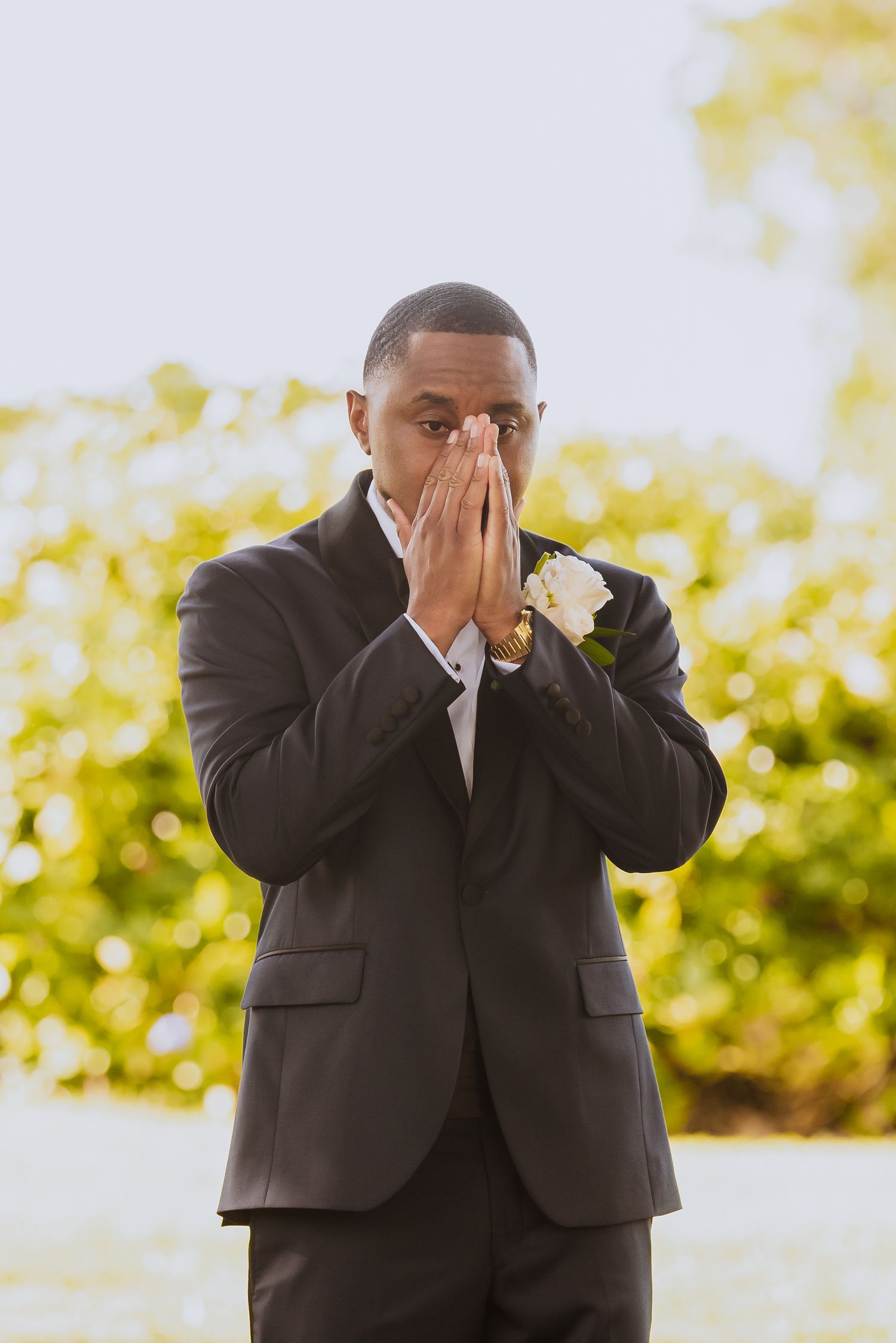 Emotional first look reaction of groom covering his face during outdoor wedding photoshoot.