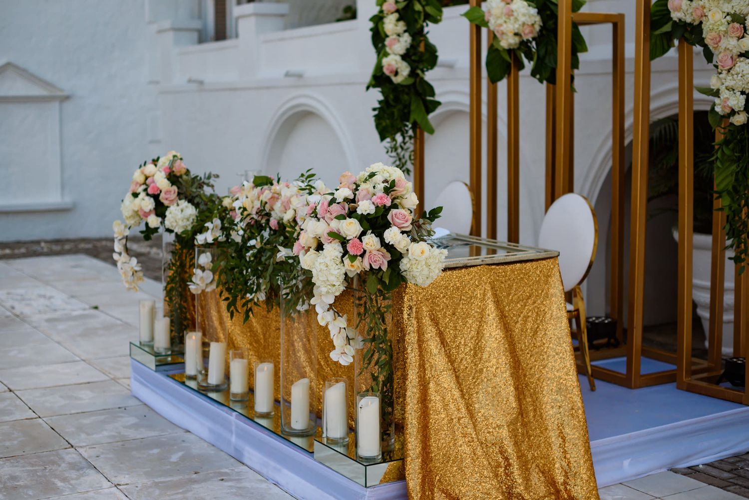 White wedding venue interior with gold accents and floral decorations along tables.