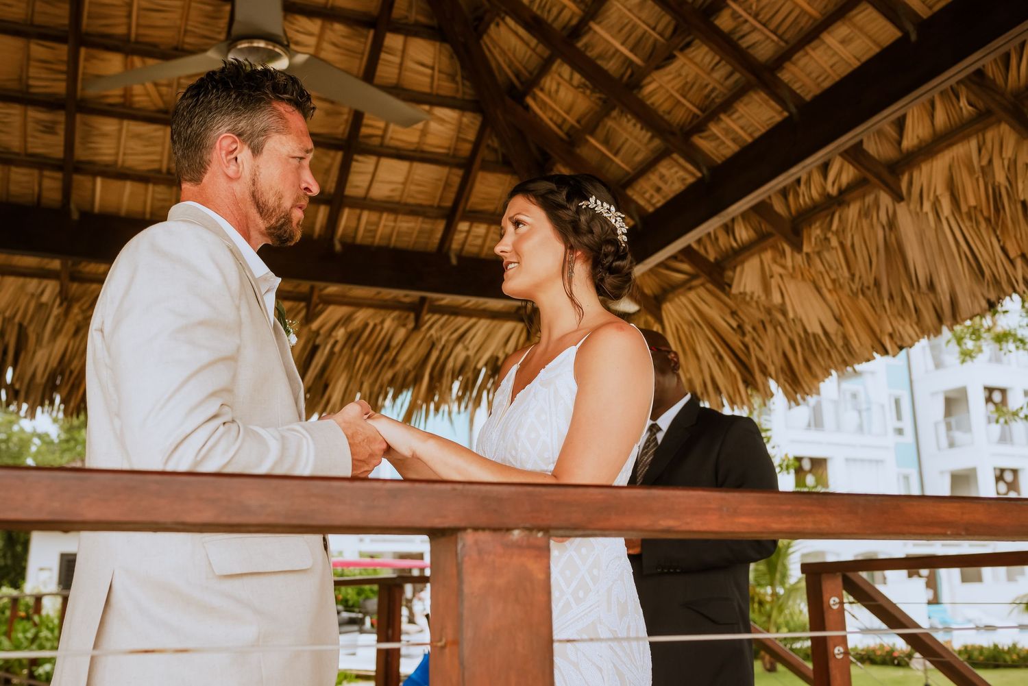 Wedding ceremony moments captured under a thatched roof palapa by the beach.