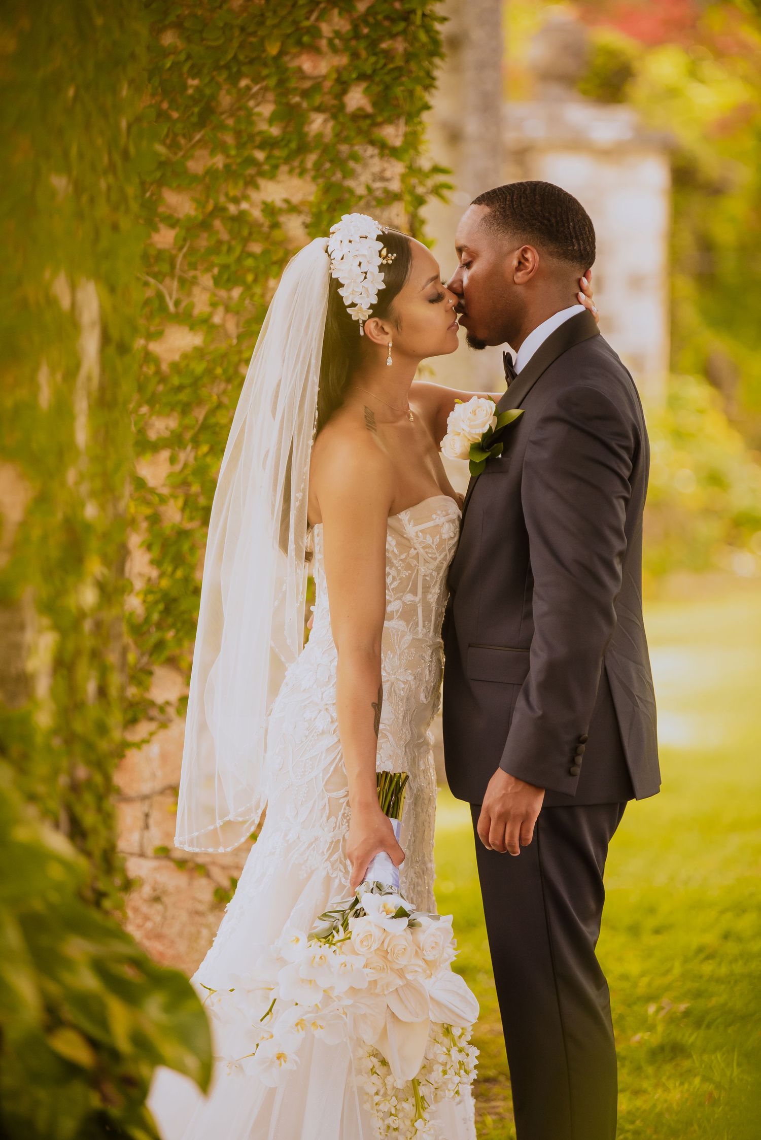 Newlyweds share a tender moment in a sun-dappled garden setting with autumn colors.