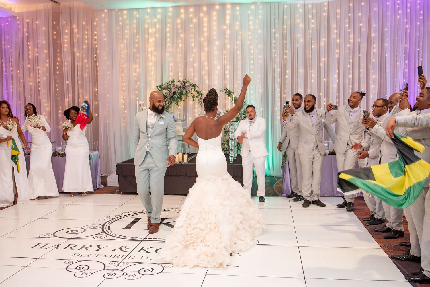 Wedding celebration on a custom dance floor with white draping and colorful lighting.