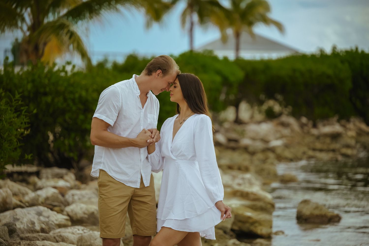 Romantic couple photoshoot along tropical rocky shoreline with ocean views.