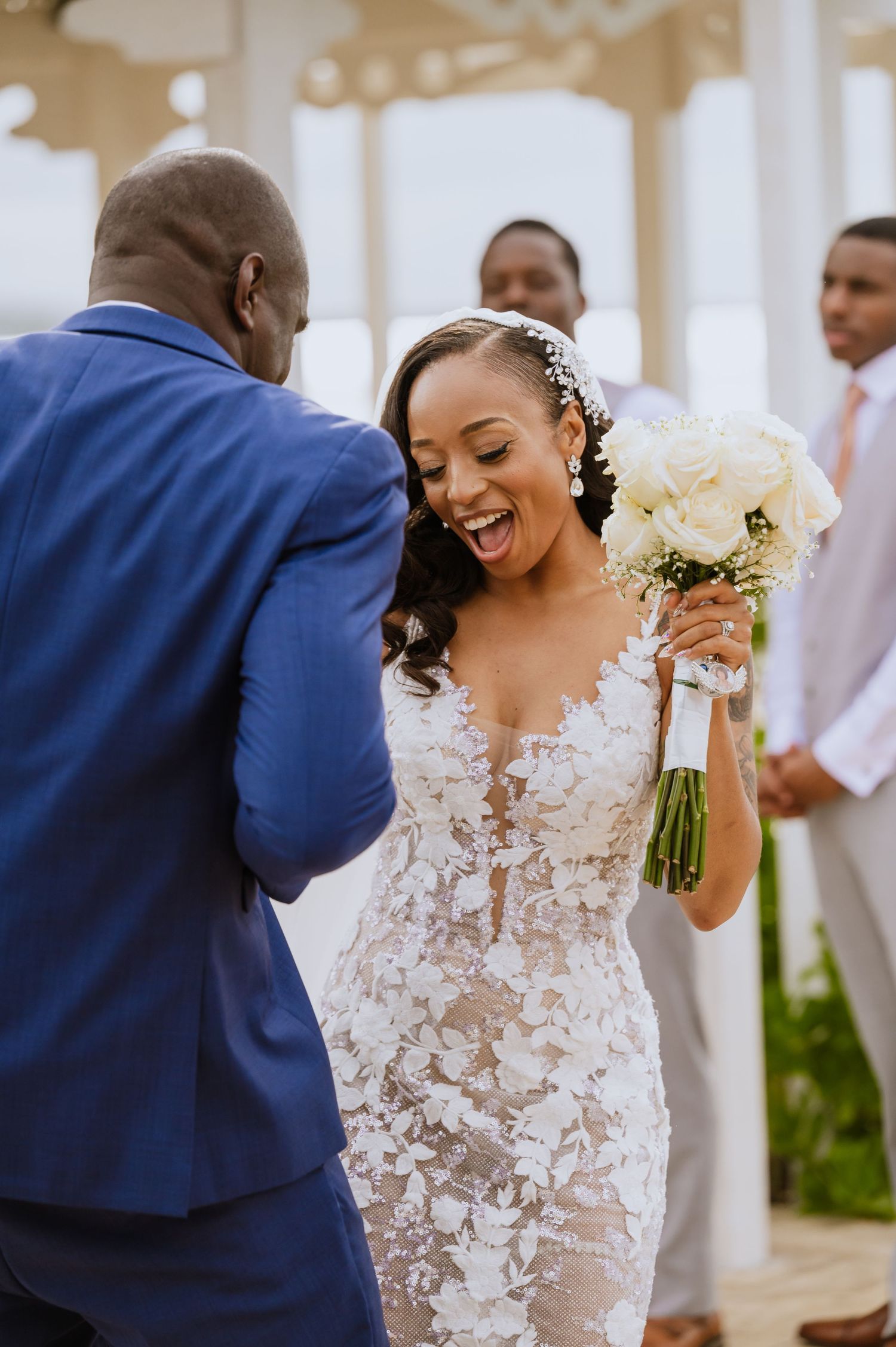 A couple shares a candid moment during their wedding ceremony under a white gazebo.