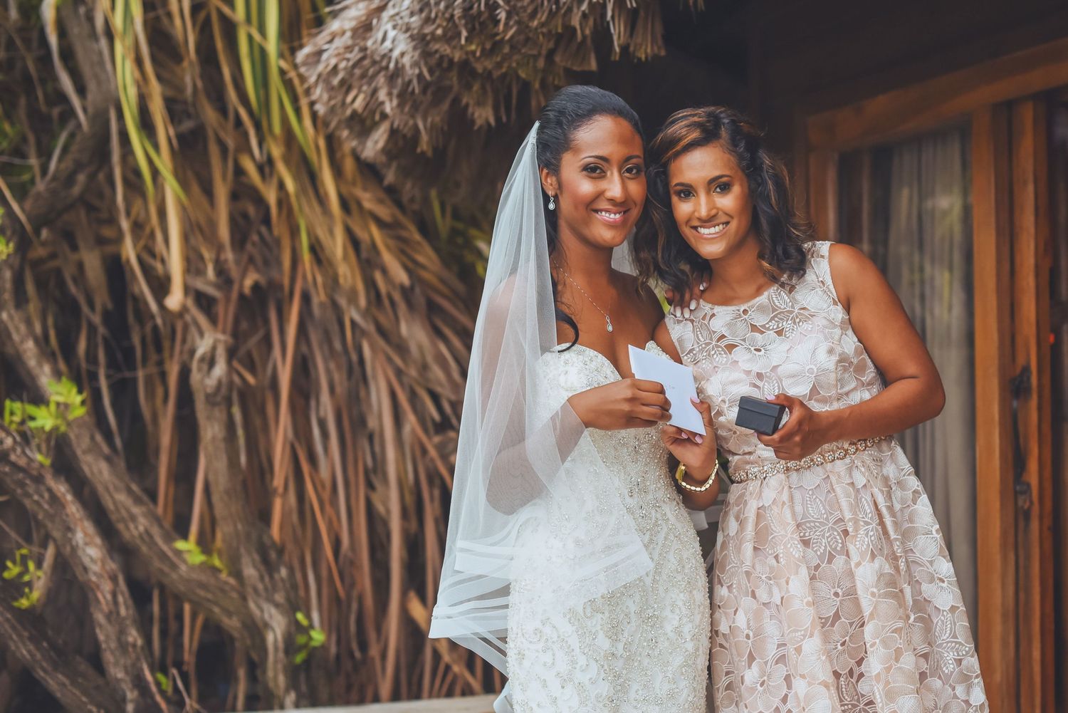 Wedding party members share joyful moments in white and blush dresses outdoors.