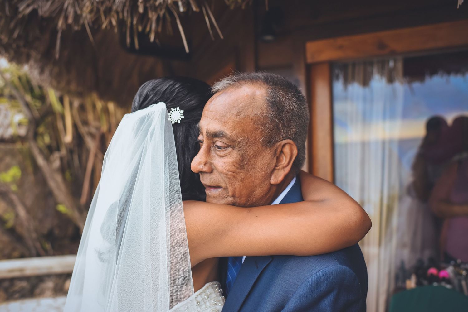 A tender moment captured during a tropical destination wedding with palm trees in background.