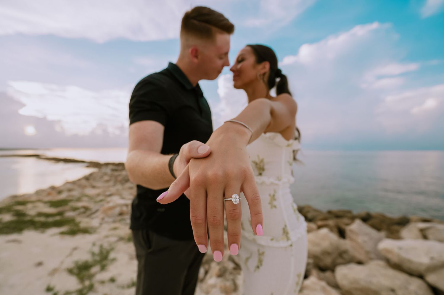 Couple embracing on rocky coastal cliffs during a romantic photoshoot.