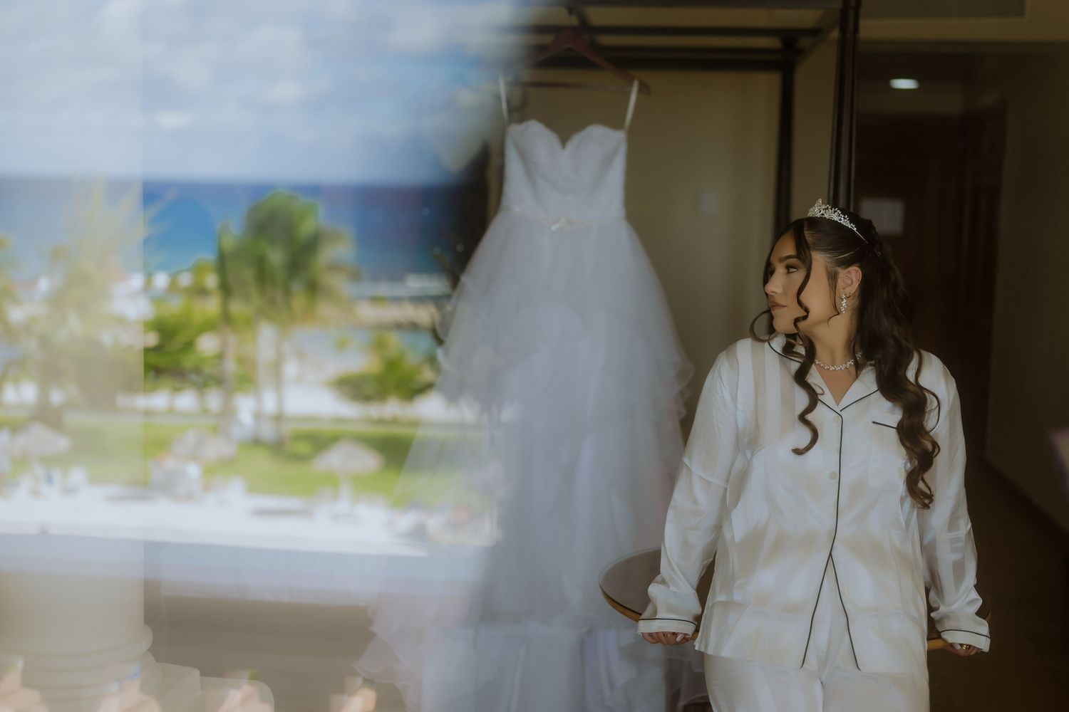 A bride in a flowing white wedding dress walks through a bright interior space with soft natural lighting.