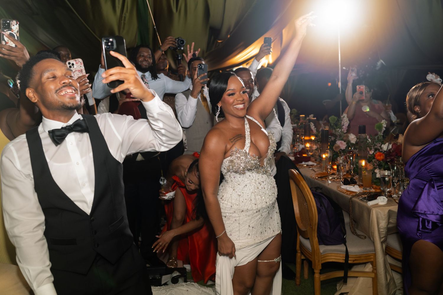 Lively wedding reception celebration with guests dancing under dramatic lighting.