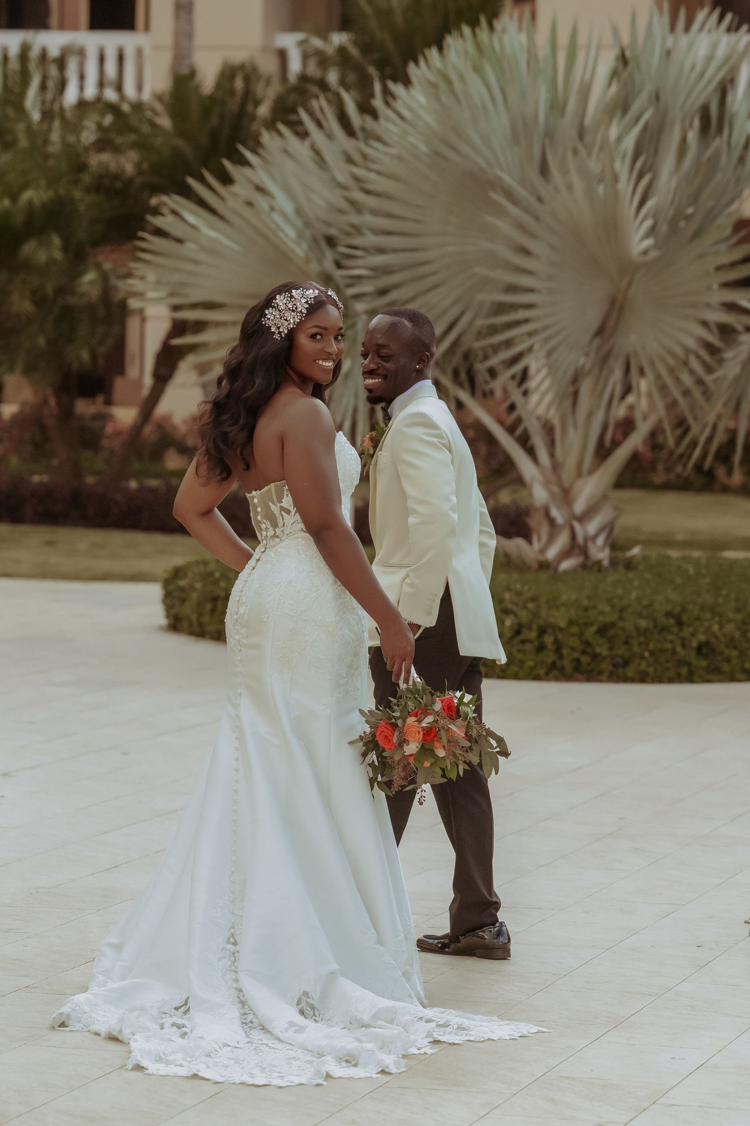 Wedding couple posing outdoors with tropical palm trees in the background.