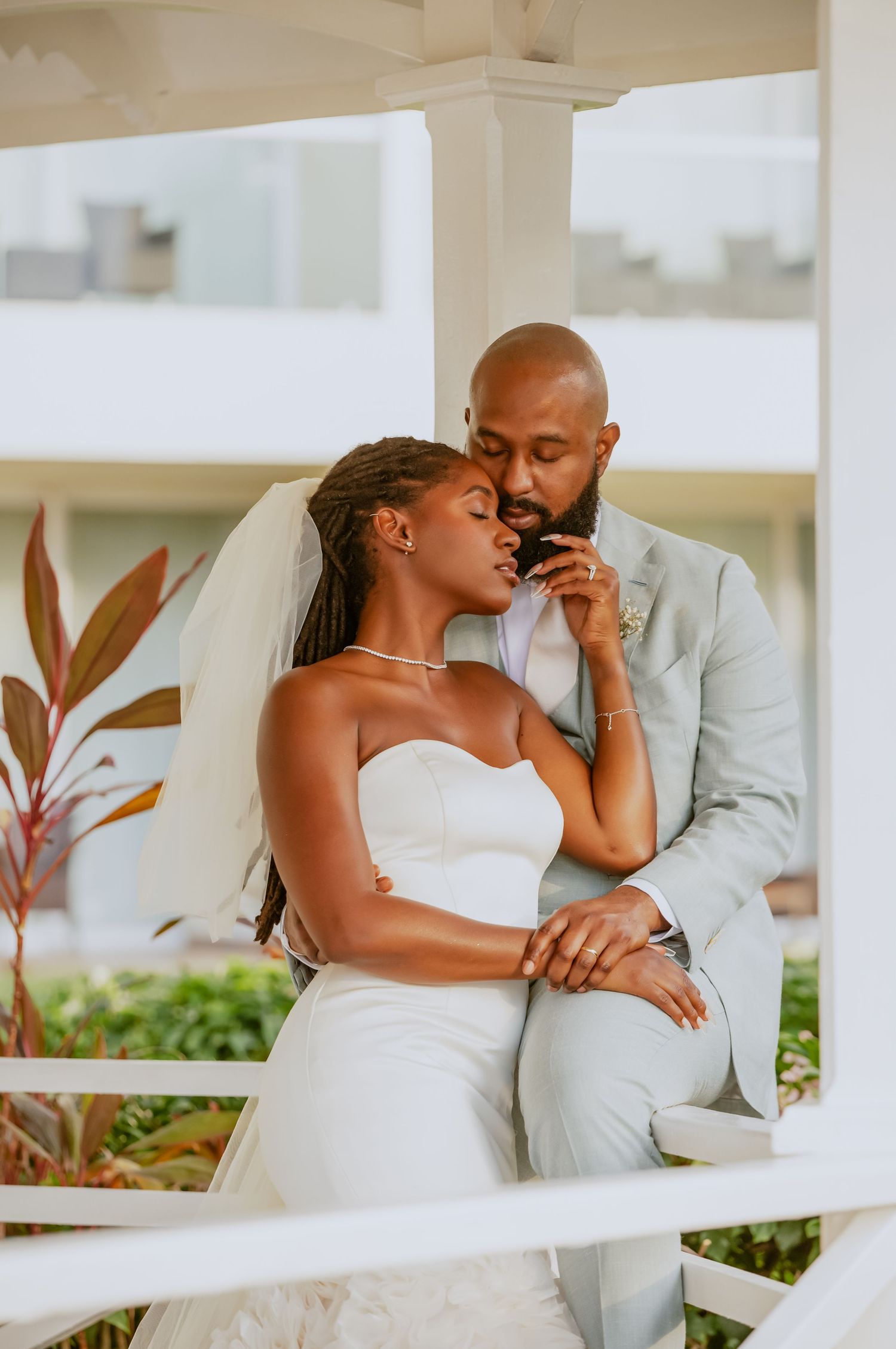 A tender wedding moment captured under a white gazebo with elegant decor and greenery.
