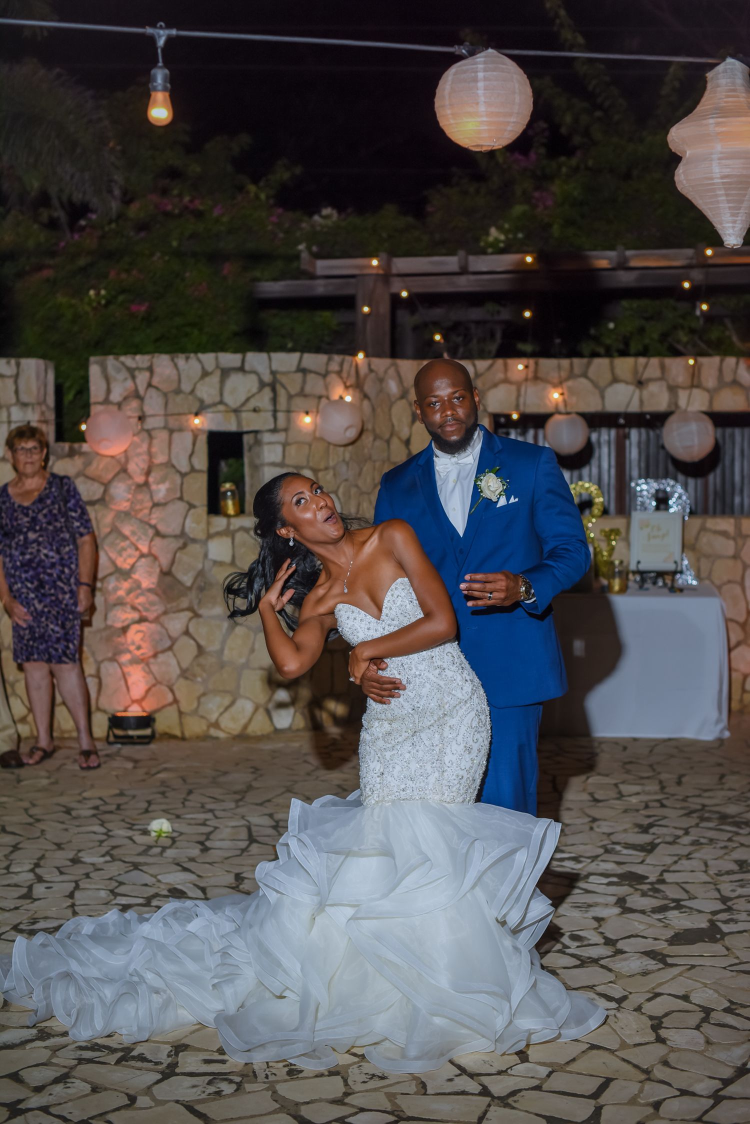 Wedding couple performing choreographed dance moves on outdoor stone patio.