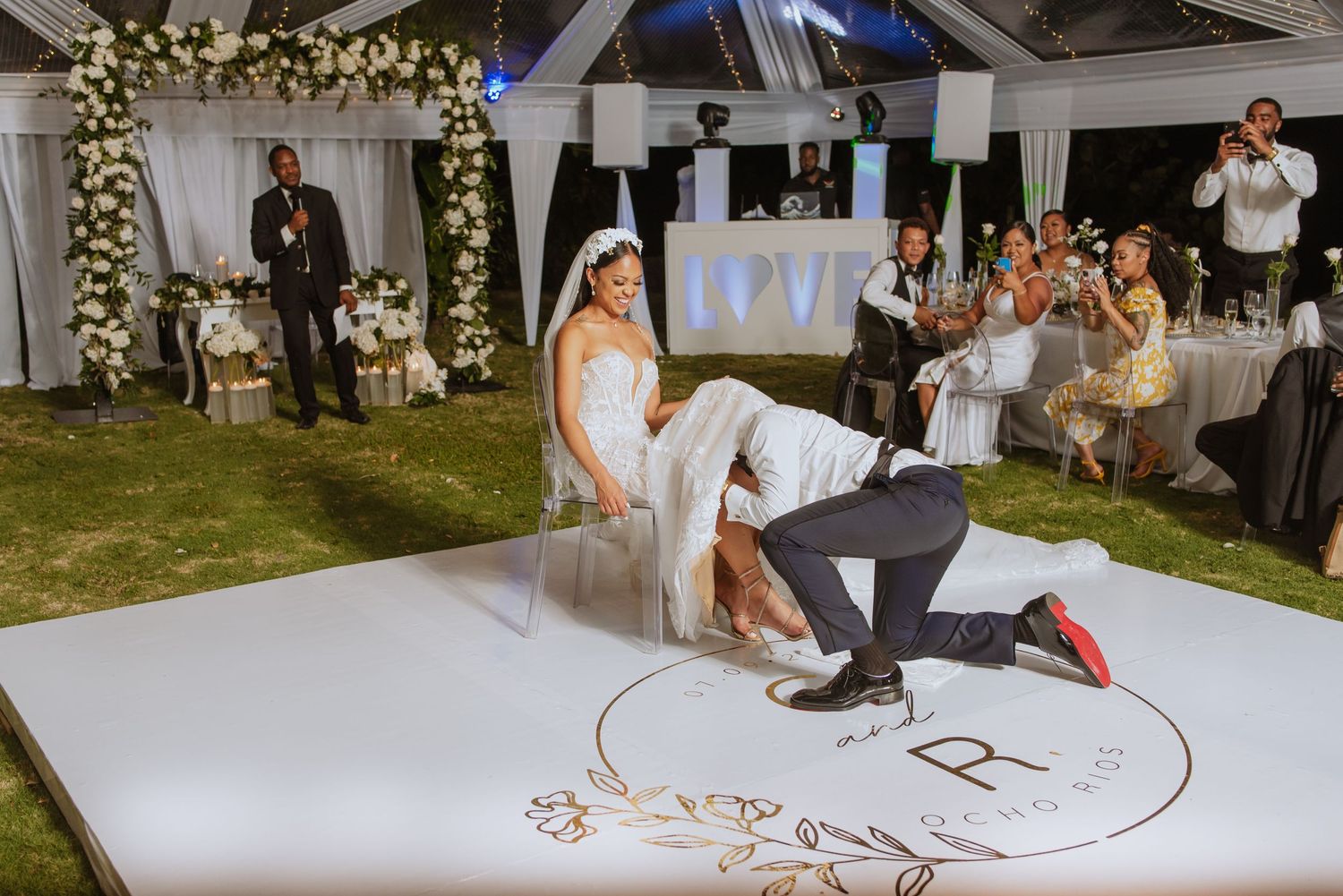 Wedding reception features fun dance moment on decorated white dance floor under tent.