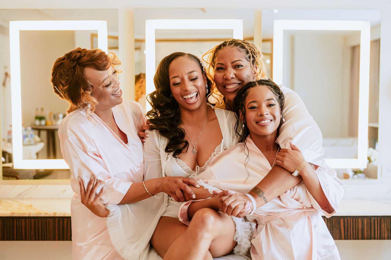 A joyful group of bridesmaids laugh and embrace while getting ready.