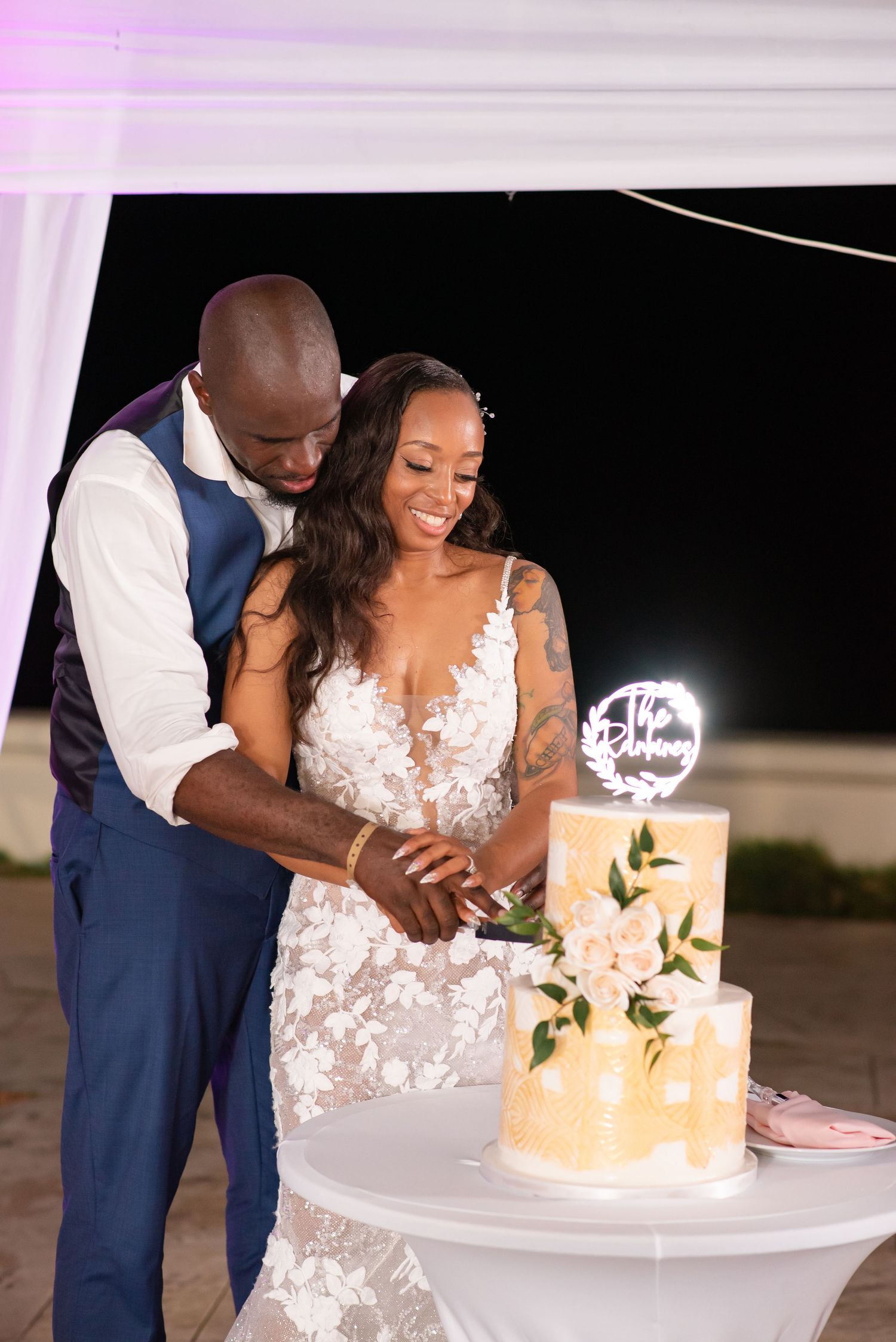 A couple shares a sweet moment while cutting their elegant gold and white wedding cake.