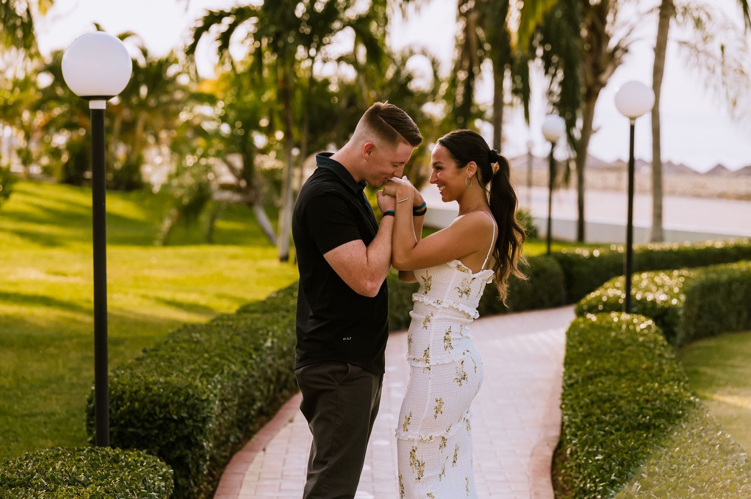 Couple sharing intimate moments during a golden hour photoshoot in a tropical garden setting.