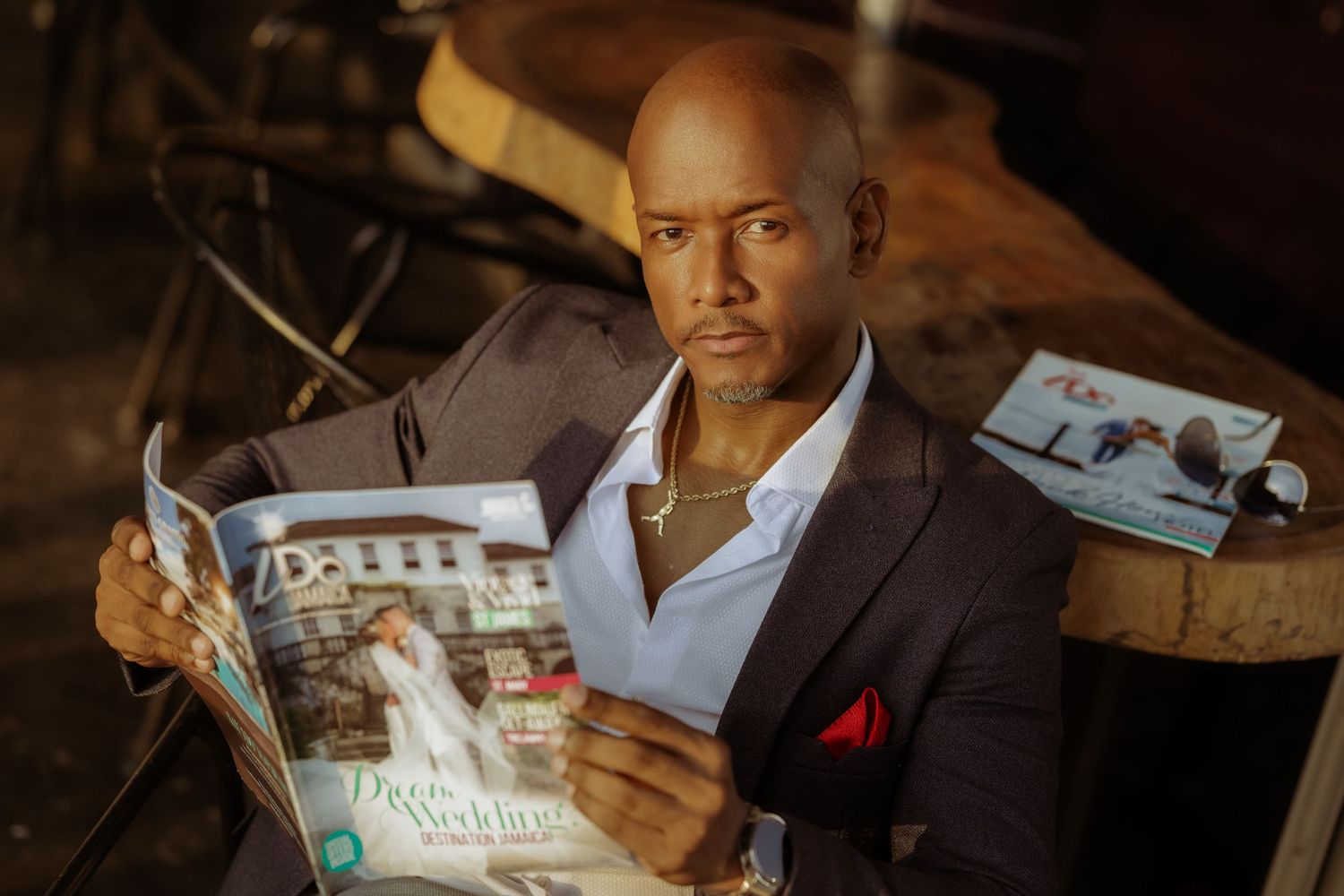 Elegant portrait of someone reading a magazine while wearing a tailored blazer with red pocket square.