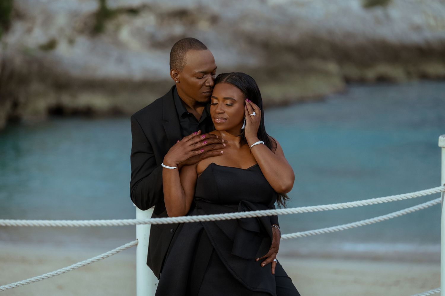 Romantic waterfront scene with a white rope railing and blue water.