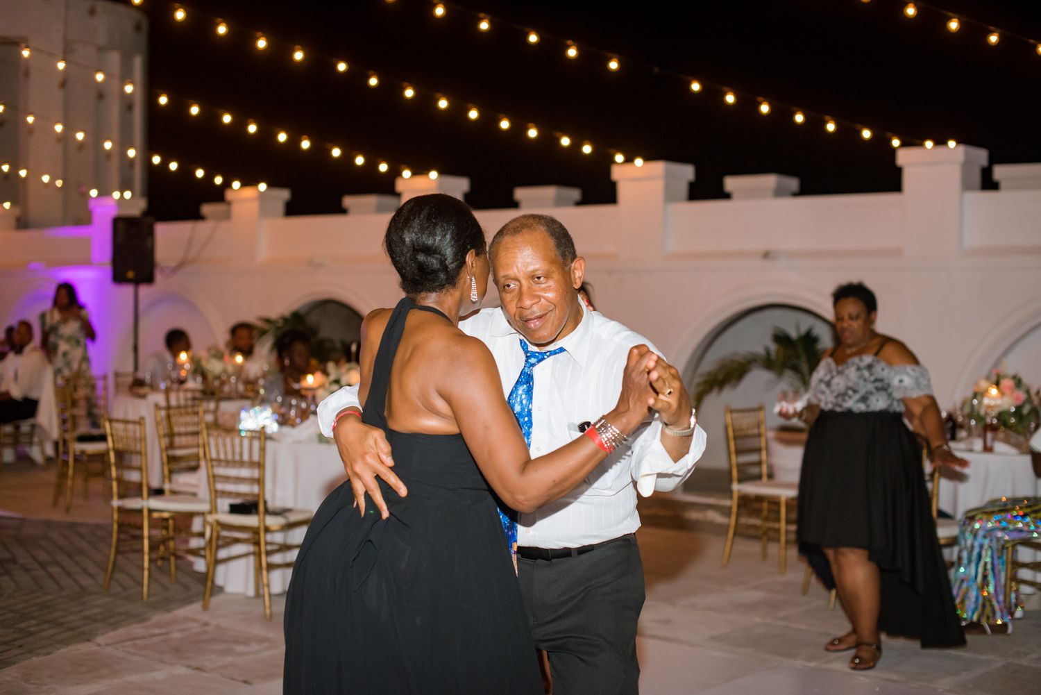 Wedding guests dancing and celebrating on an outdoor reception dance floor.