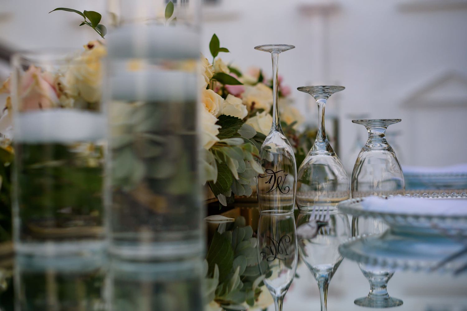 Crystal glassware and elegant table settings arranged for an upscale wedding reception.