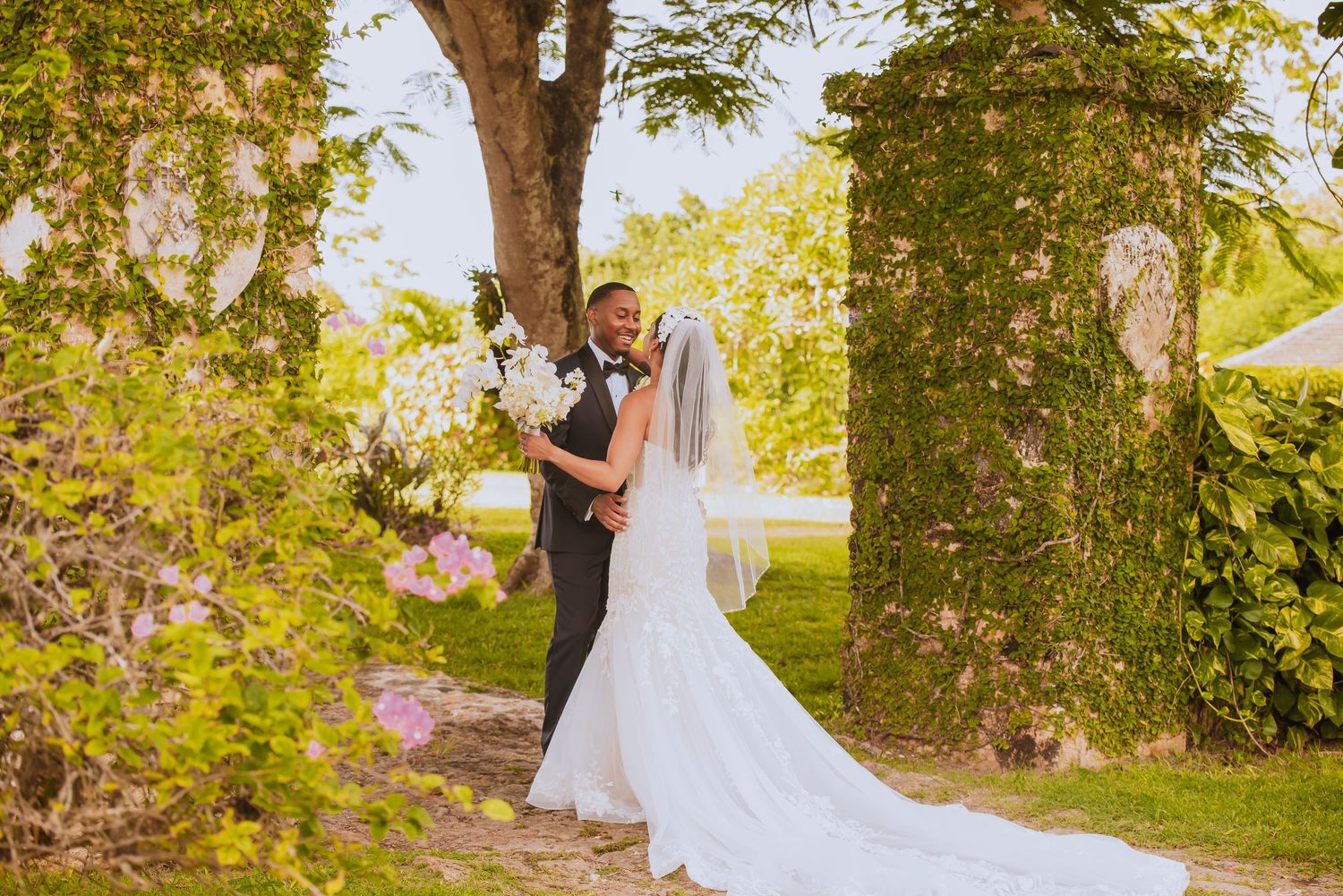 Couple embracing during their first look wedding moment under trees with golden sunlight.
