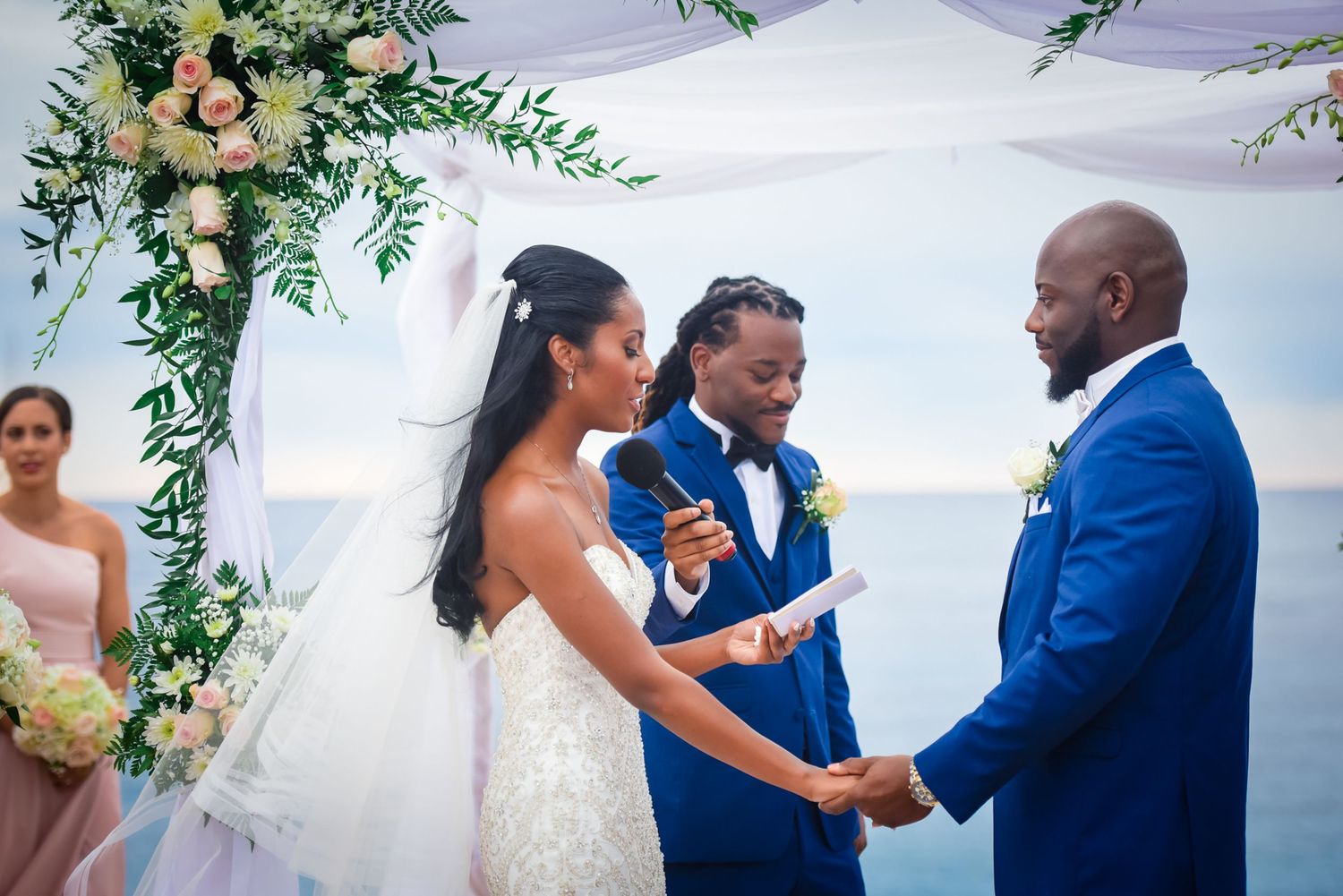 Emotional wedding ceremony moment under white canopy with floral decorations and greenery.