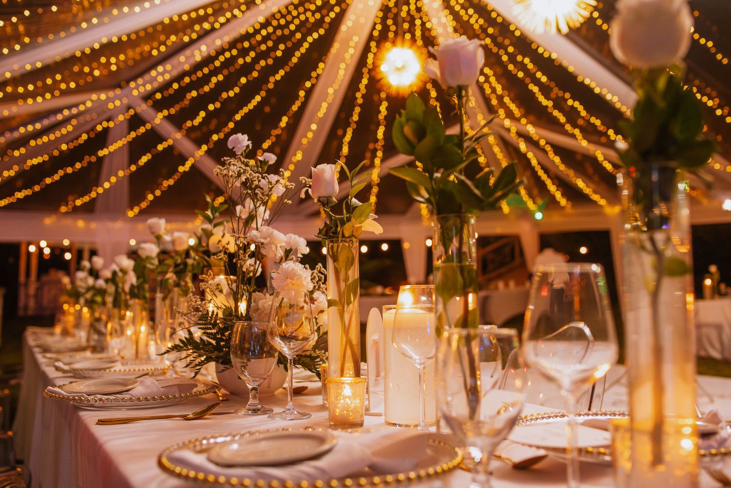 Romantic reception setup with overhead string lights creating a starry effect above elegant table settings.