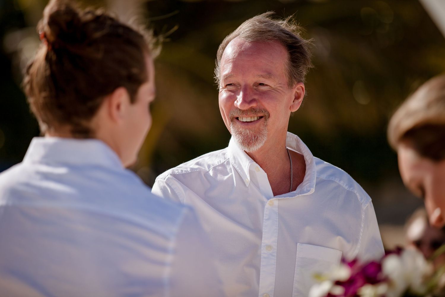 Wedding ceremony moments captured on a sunny beach with guests in casual attire.