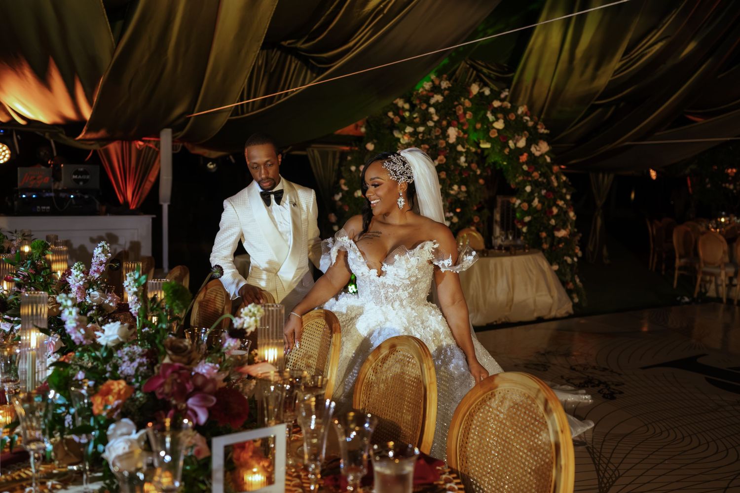 Dimly lit reception venue with dramatic floral arrangements and romantic lighting.