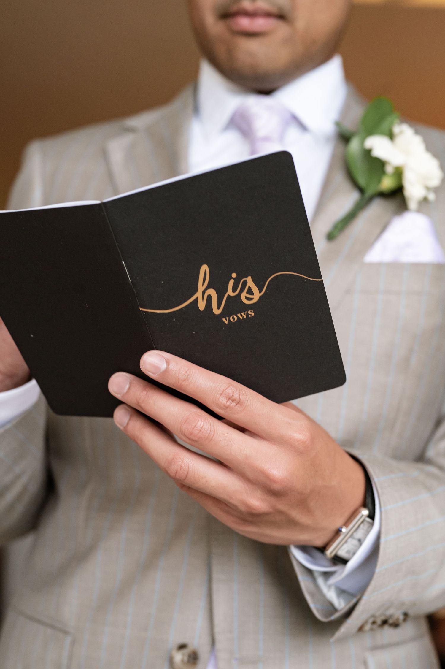 Wedding vow books with elegant gold lettering held in formal attire.