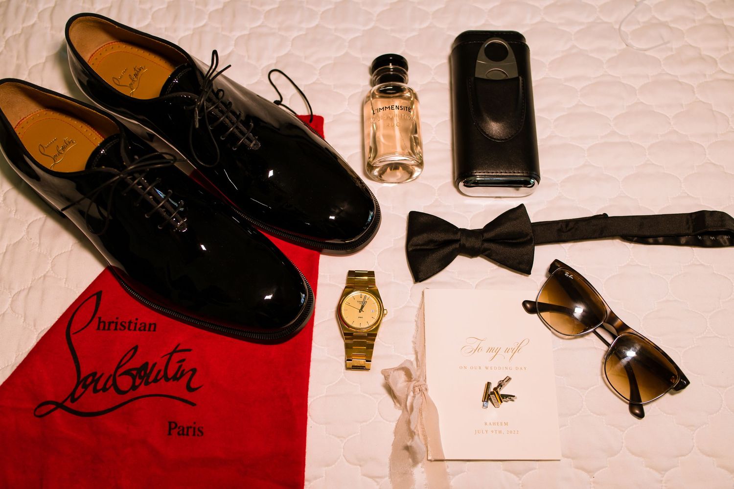 Wedding accessories including shoes, bow ties, and cologne arranged on white surface.