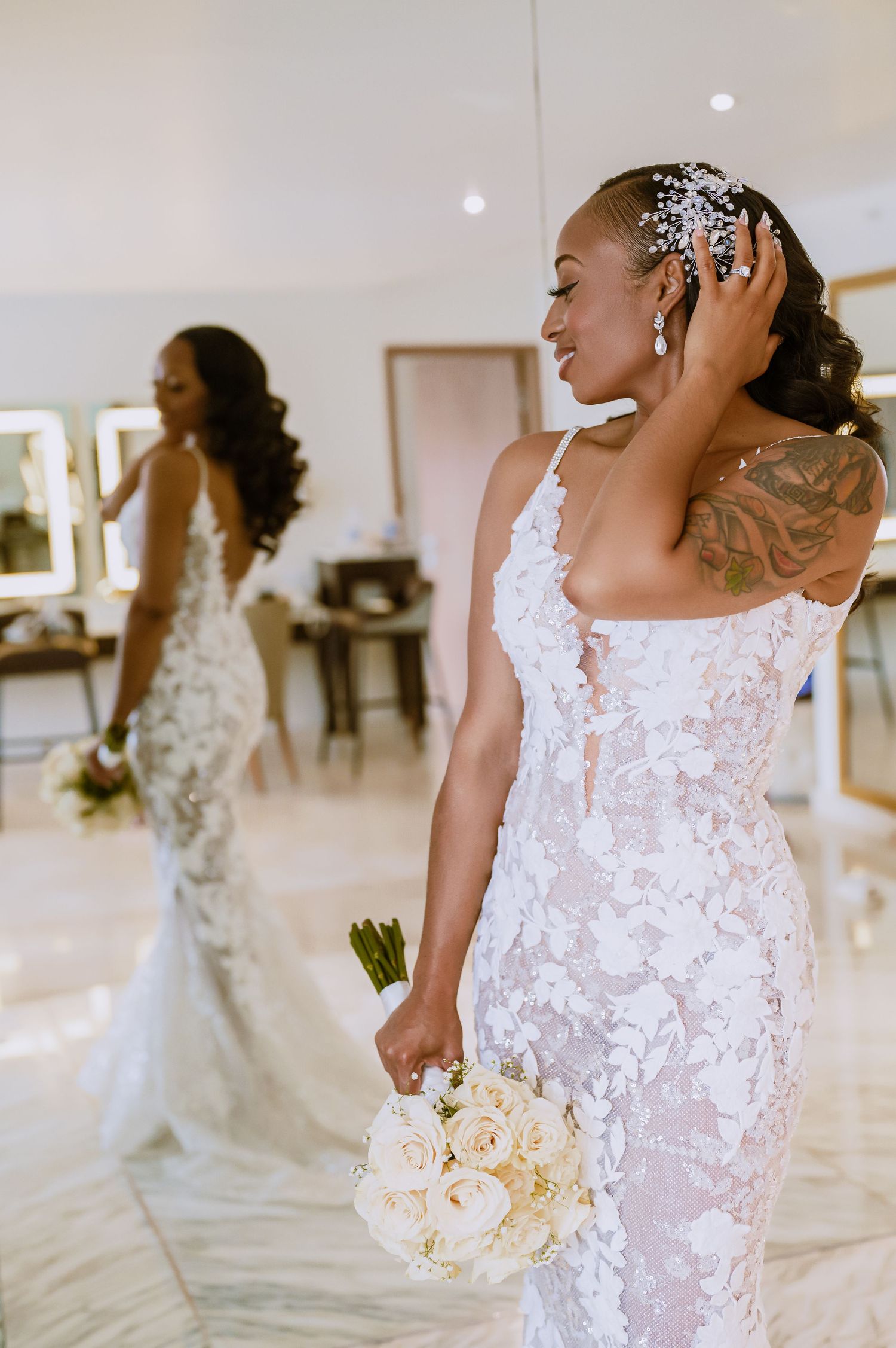 Side view of a lace wedding dress with floral appliques and a bouquet.