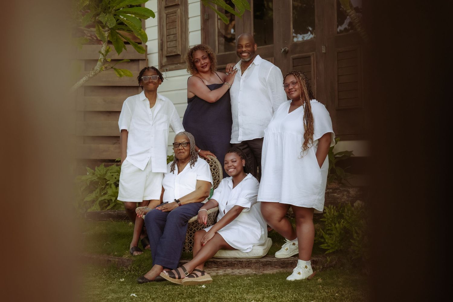 Family portrait on outdoor steps in coordinated white outfits.