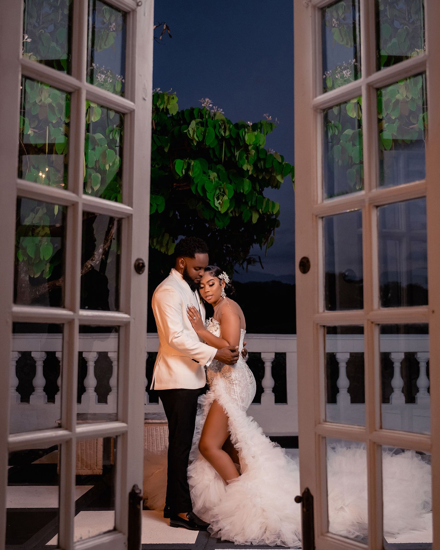 A couple shares an intimate moment in front of French doors at an elegant venue during their wedding celebration.