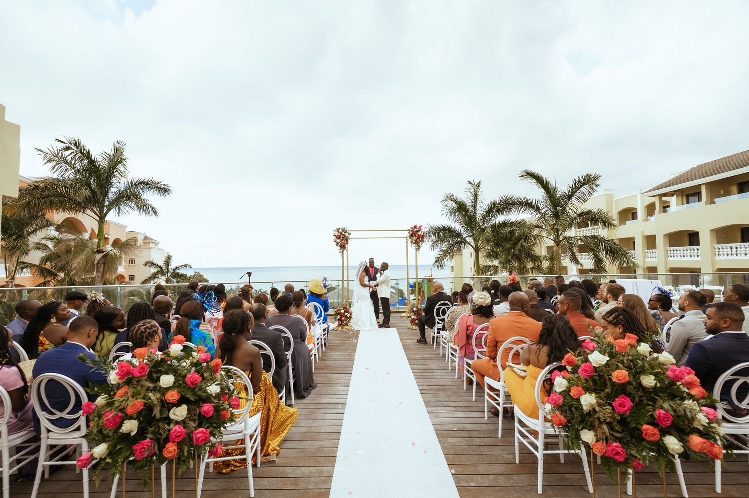Outdoor beach wedding ceremony setup with white chairs and floral arrangements.