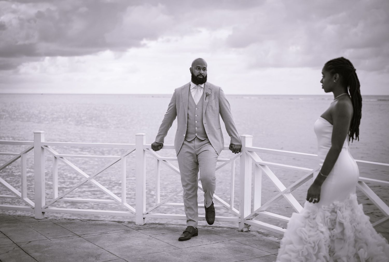 Black and white wedding photos showing poses along a seaside railing.