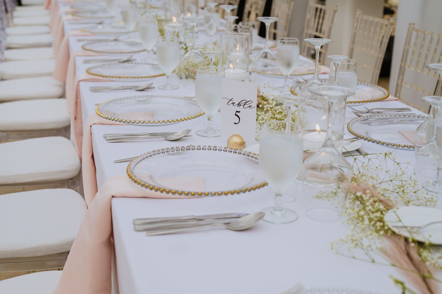 Wedding table settings with beaded charger plates and delicate floral arrangements on white linens.