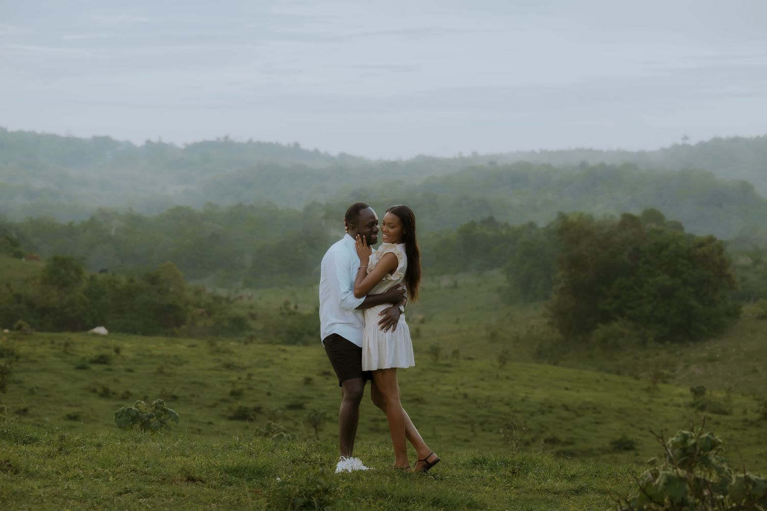 Couple walking along scenic hilltop path with mountain views.