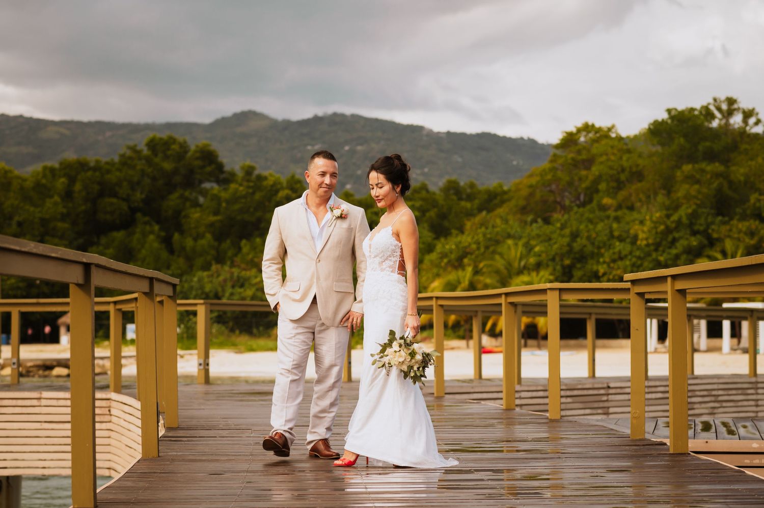 Wedding photography session on resort boardwalk with mountain and ocean backdrop.