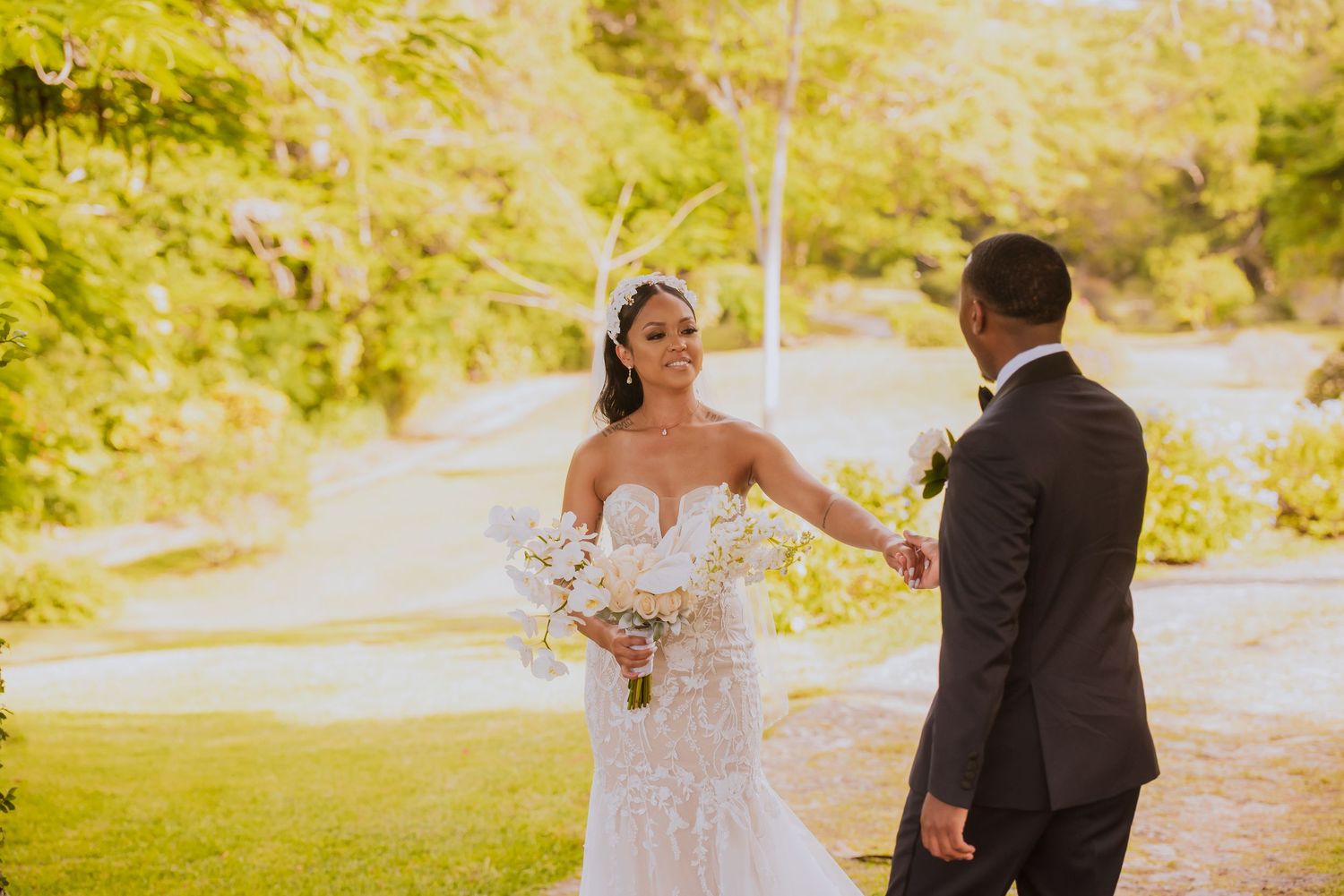 Bride and groom's emotional first meeting captured in sunlit outdoor setting.