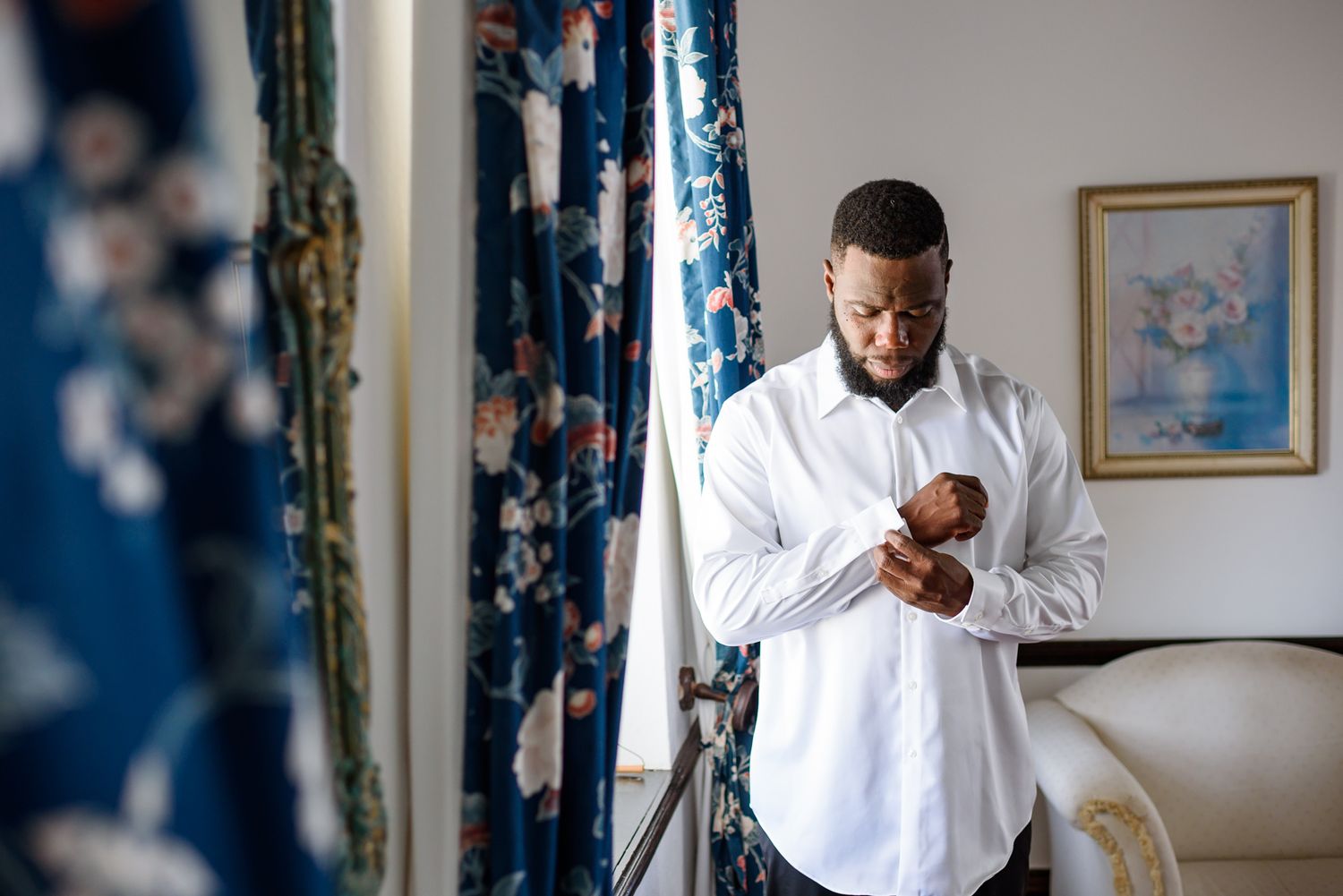 Two people in white dress shirts preparing for a formal event in an elegant room.