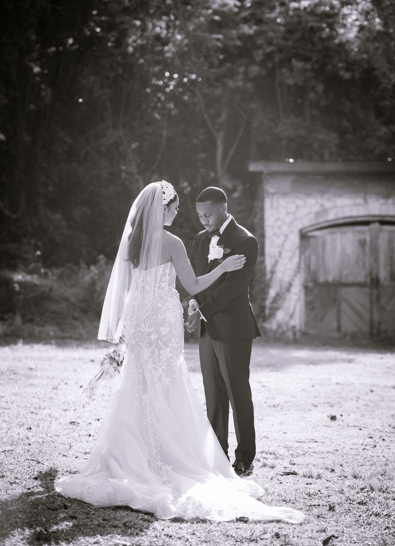 Black and white wedding photo of a couple dancing in an outdoor garden setting.