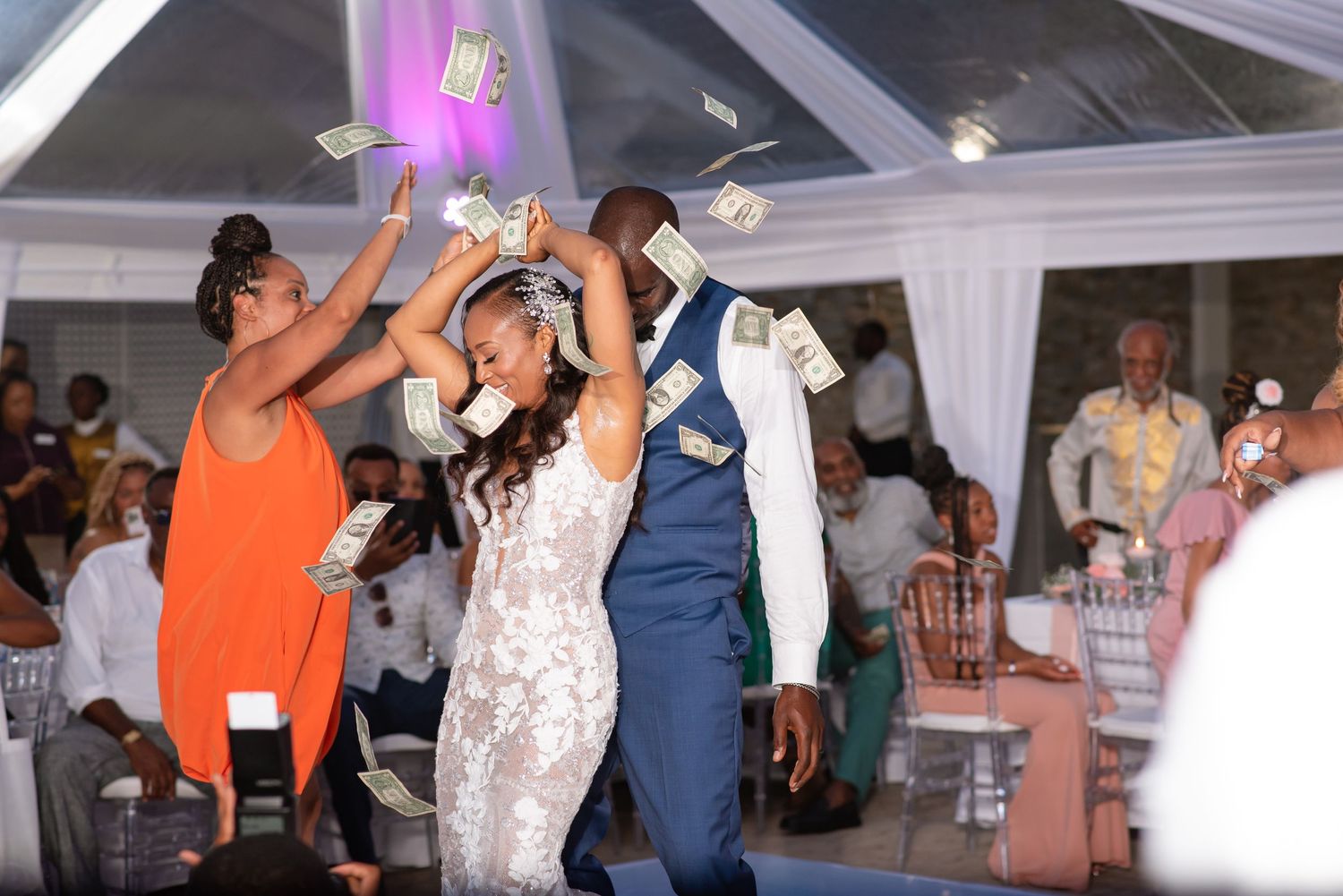 Wedding party dancing and celebrating in decorated outdoor tent venue.