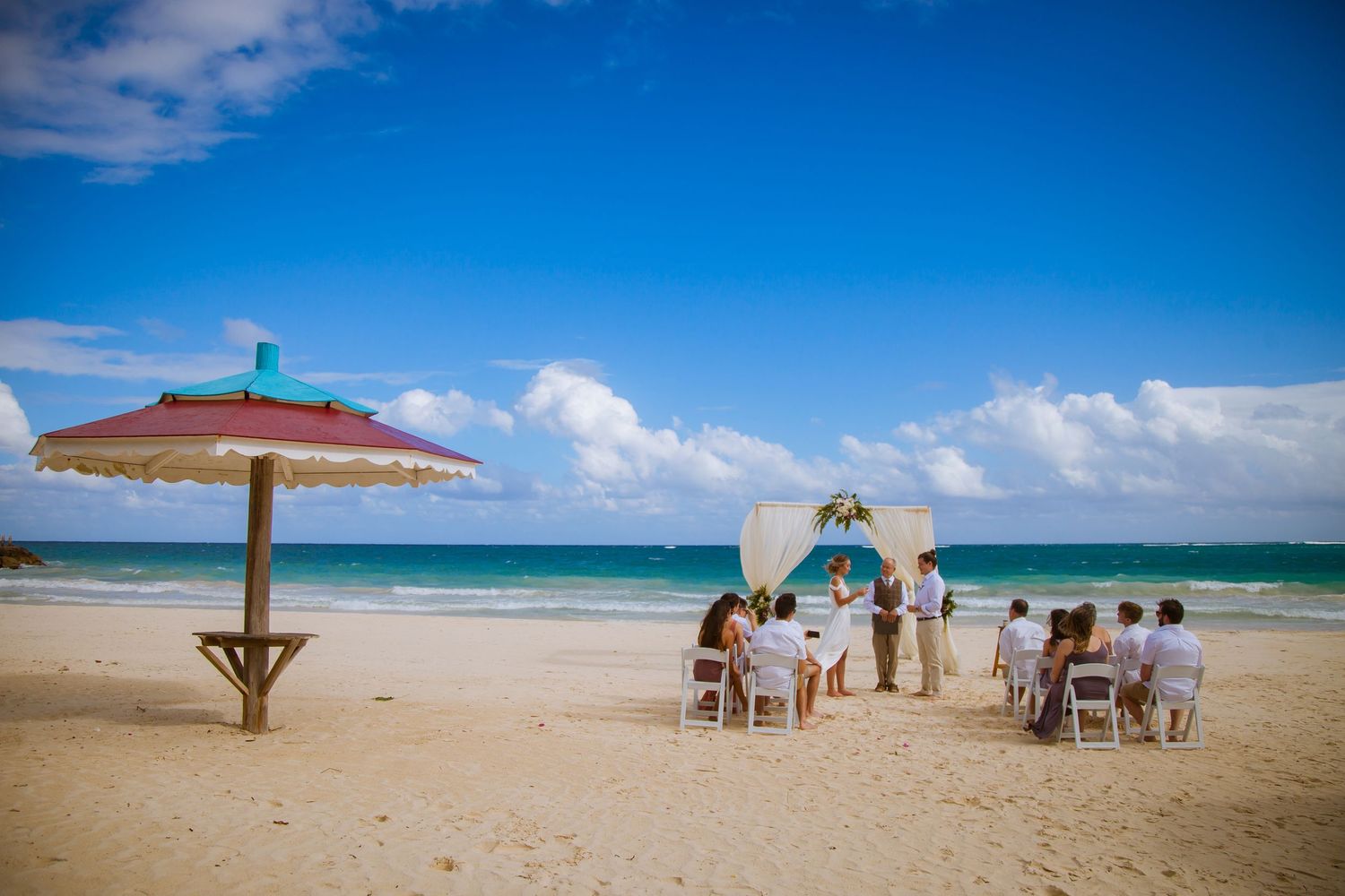 Panoramic view of a destination beach wedding with blue skies and white sandy beach.