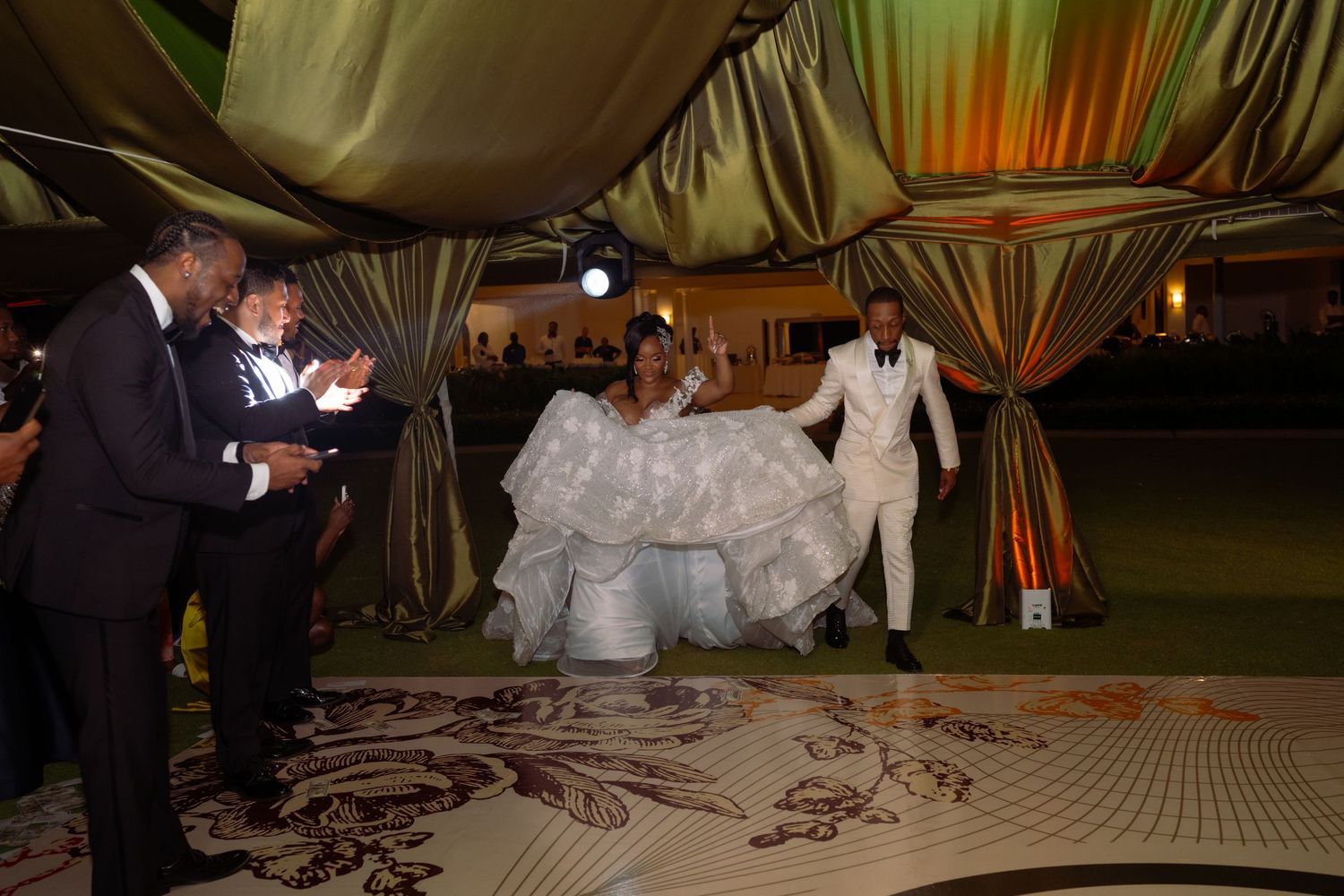 Wedding reception dance floor with dramatic lighting and decorative drapery.