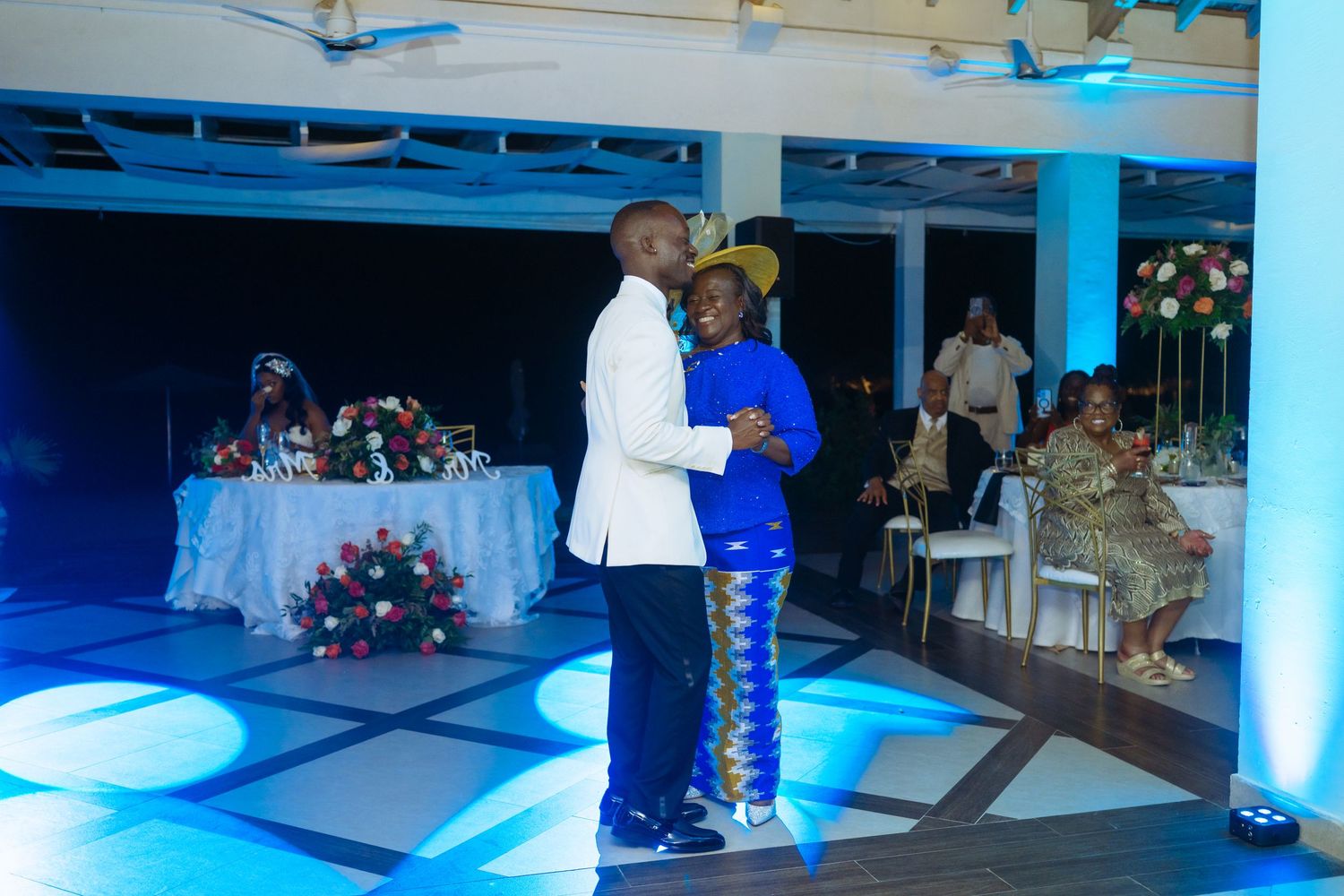 Wedding reception dance floor illuminated with blue lighting and guests dancing.