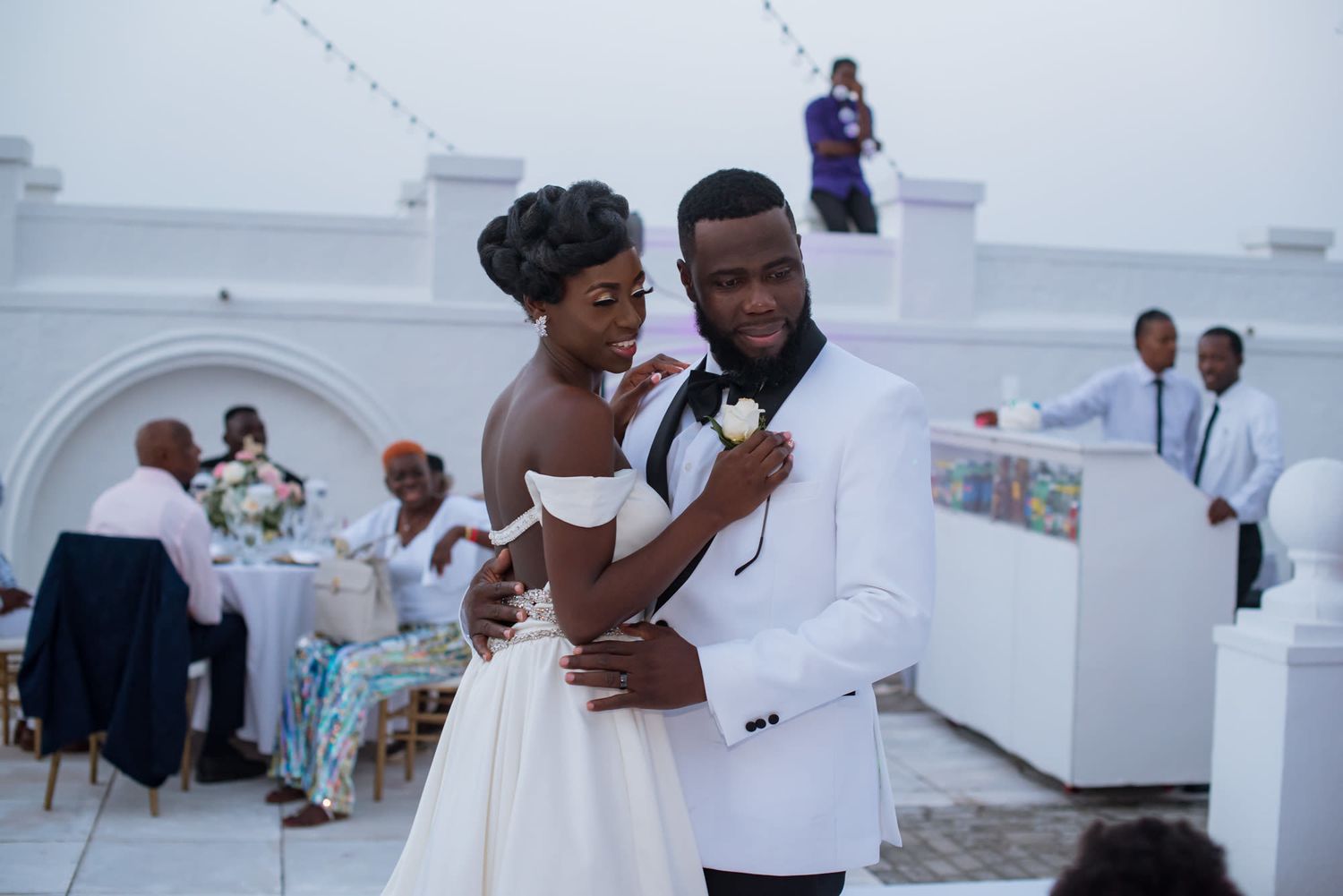Wedding celebration moments captured on an outdoor terrace with white architecture.