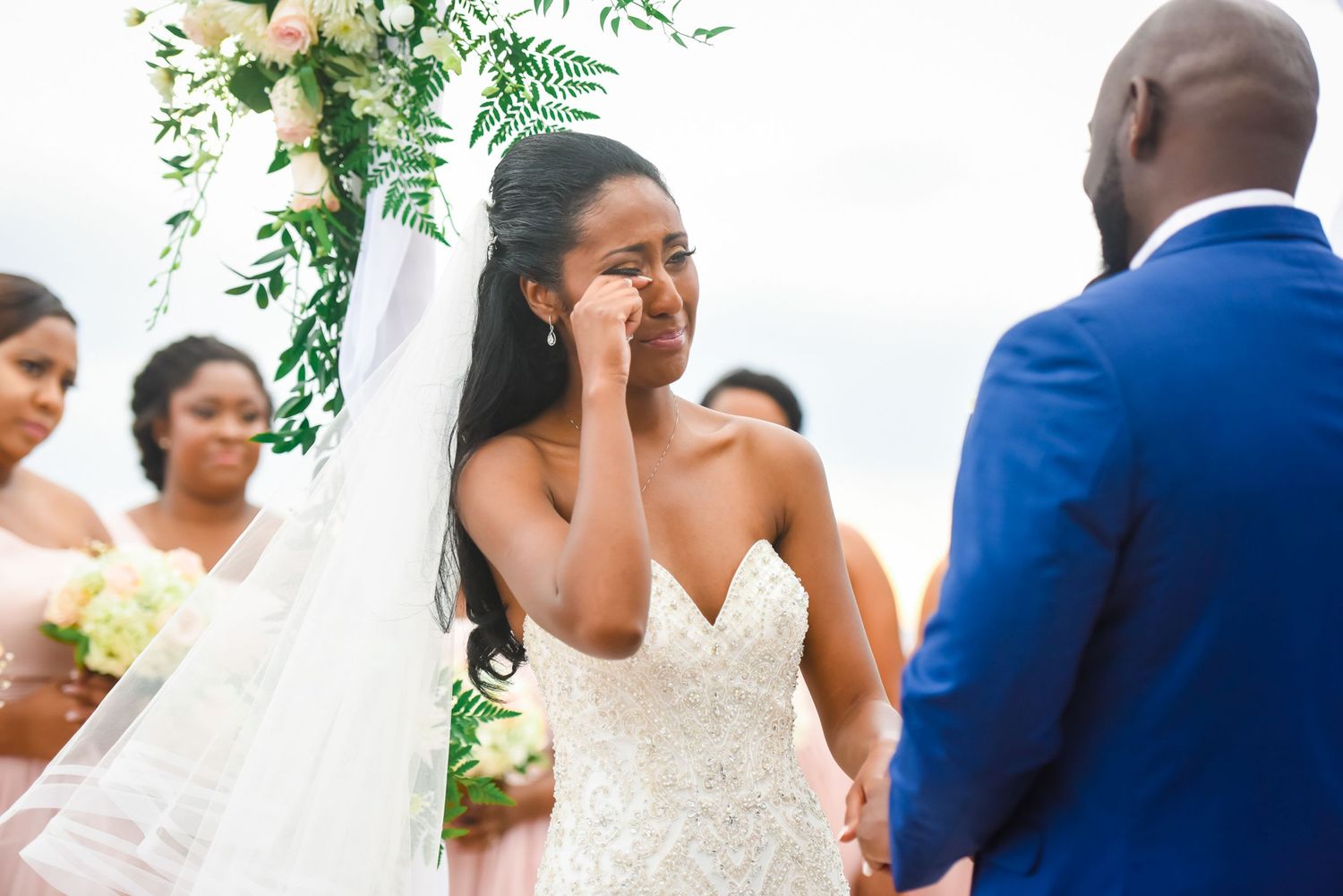 Wedding ceremony under white canopy with floral arch and delicate greenery accents.